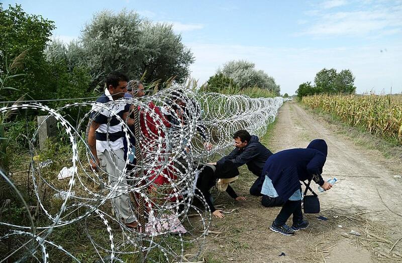 Migranci przechodzą przez drut żyletkowy