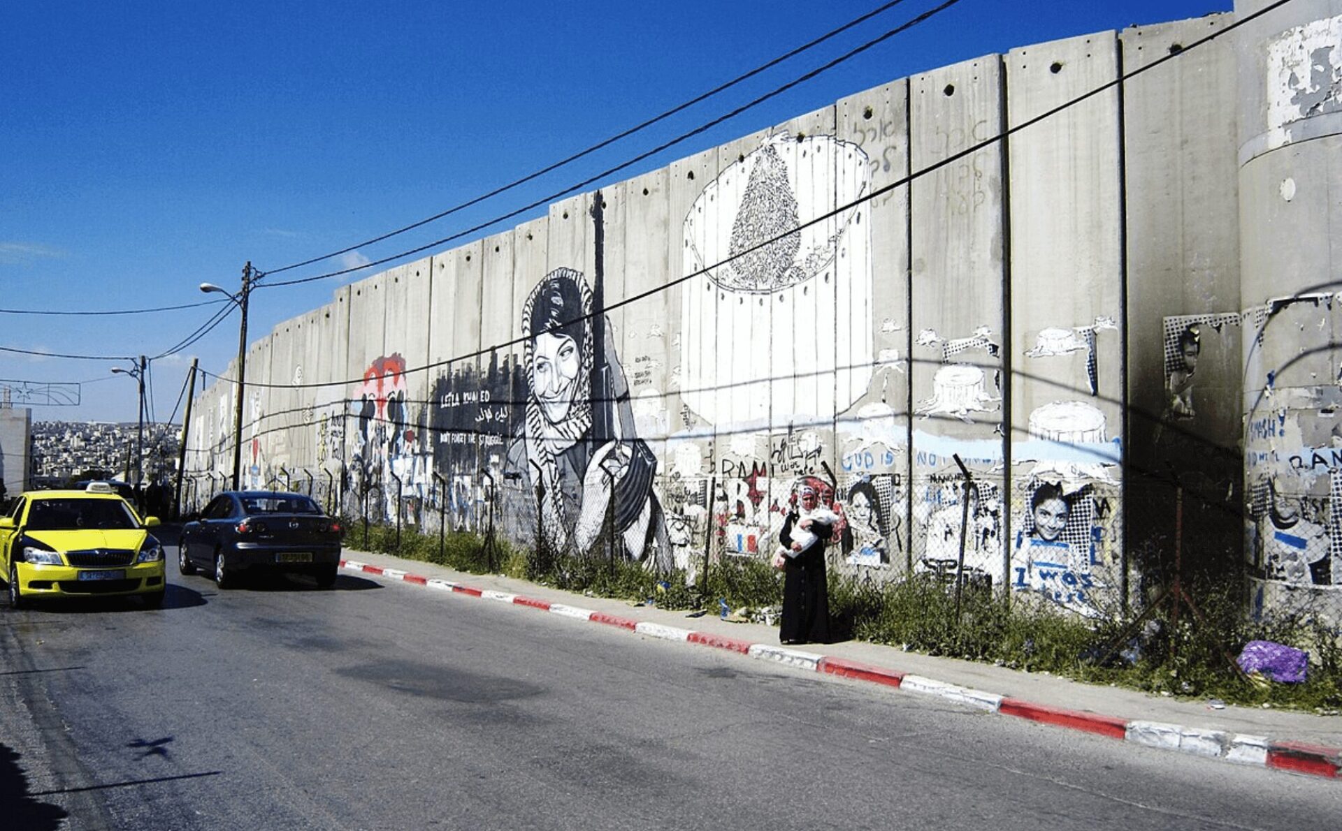 mur z graffiti na tle błękitnego nieba i obok betonowej drogi