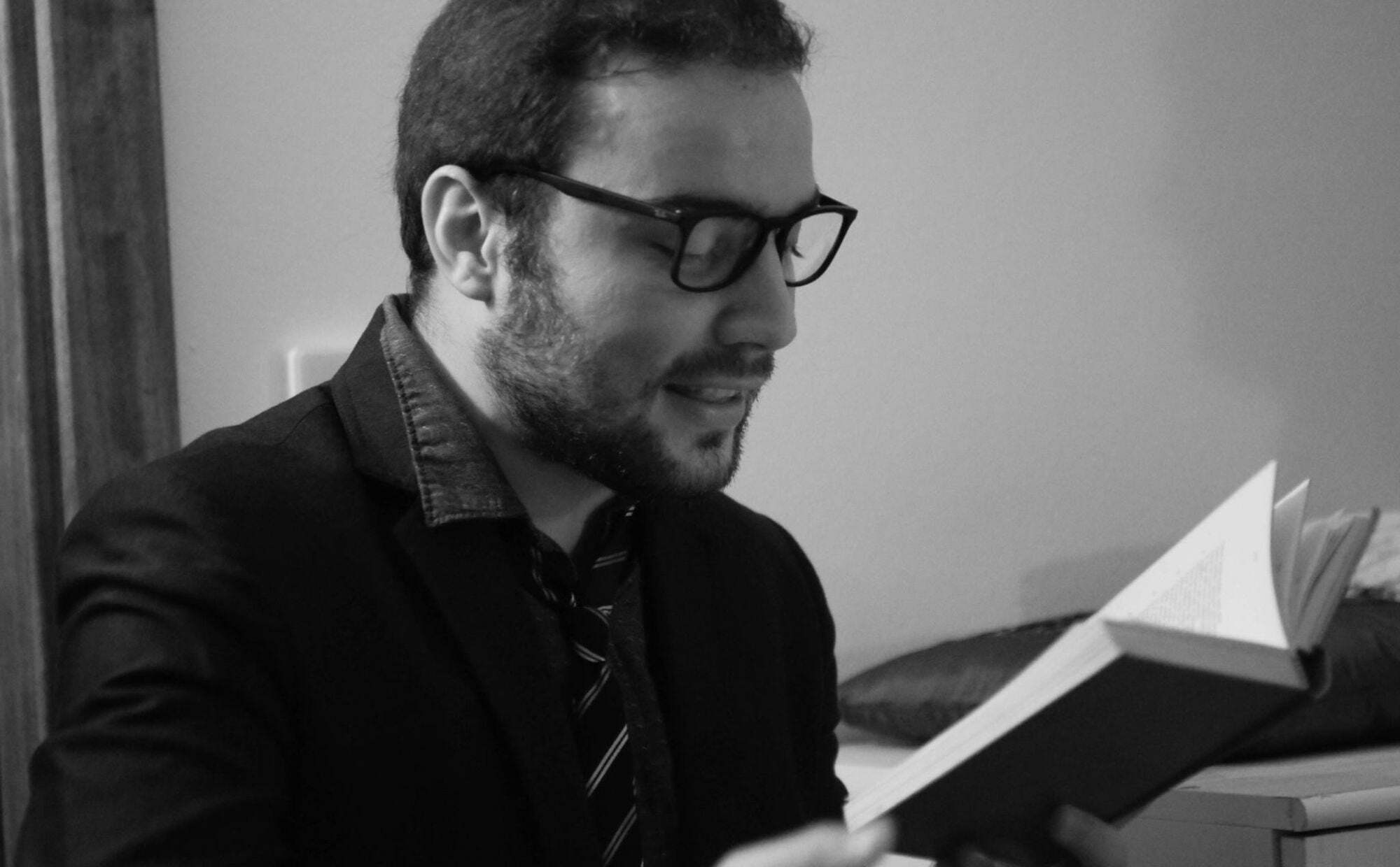 mężczyzna w okularach czytający książkę, fotografia czarno-biała