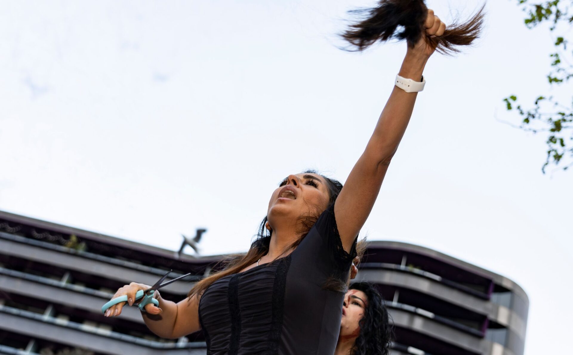 Iranka podnosi pukiel włosów, które obcięła sobie nożyczkami. Rocznica śmierci Jiny Mahsy Amini