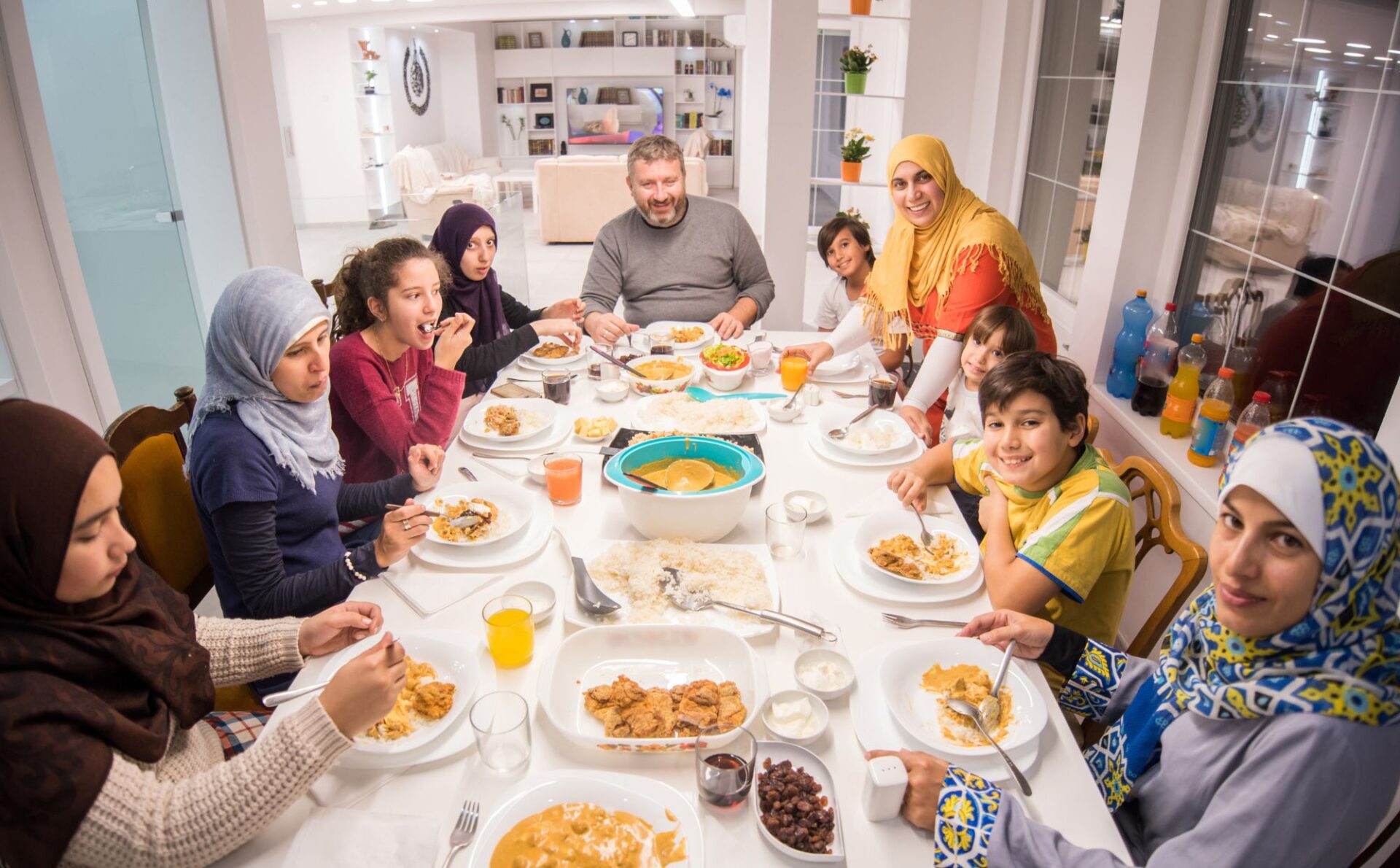 kolacja muzułmańskiej rodziny, wszyscy siedzą przy suto zastawionym stole z wieloma posiłkami